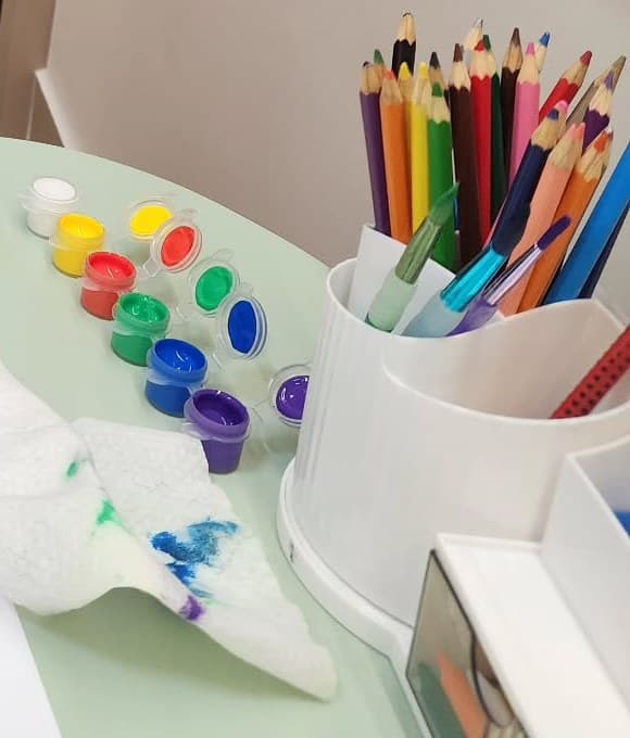 Lápis de cor e potes de tinta na mesa do canto das crianças