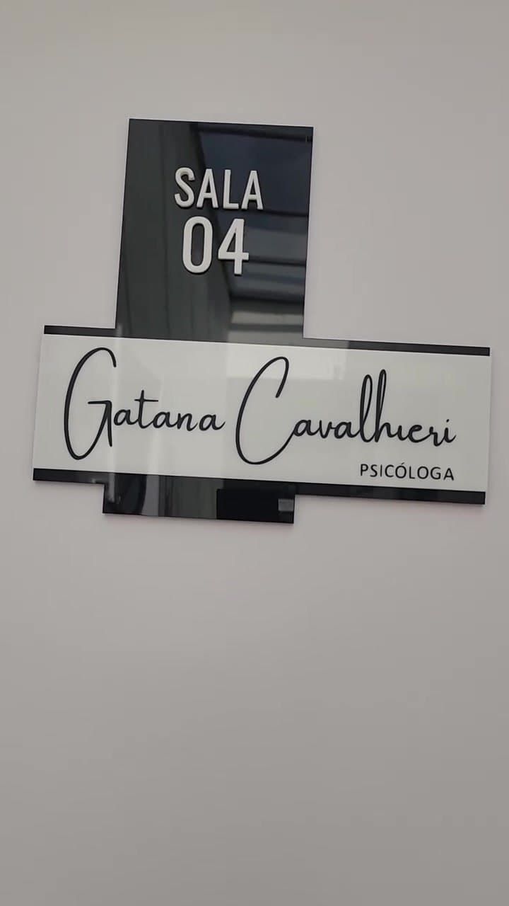 Placa de acrílico na porta do consultório com o nome Gatana Cavalhieri, psicóloga