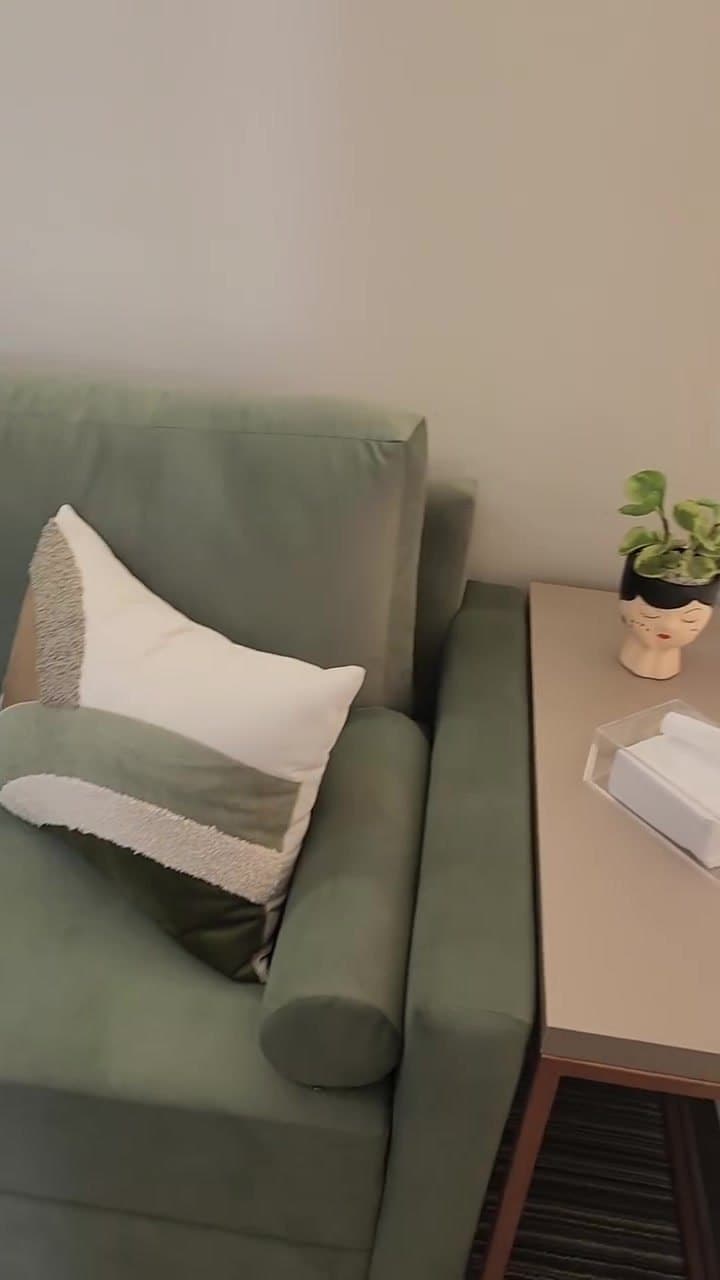 Sofá de veludo verde com almofada clara no consultório